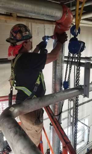 Worker in safety gear operating a hoist in an industrial setting.